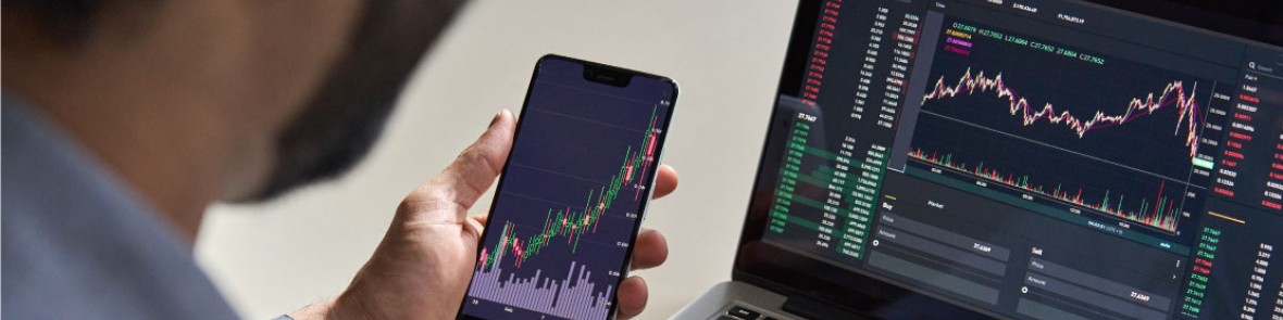 Person sat at desk with laptop and devices showing various charts and analytics